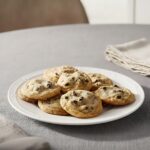 Buttery chocolate chip cookies on a white plate, homemade cookie recipe, delicious baked treats.