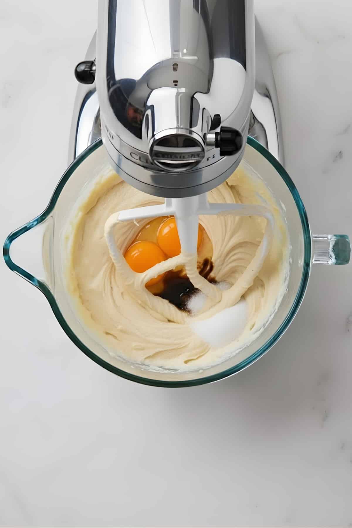 Beater mixing cookie dough with eggs and vanilla in a glass bowl, stand mixer, baking ingredients, pastry preparation, AllCookiesRecipes.