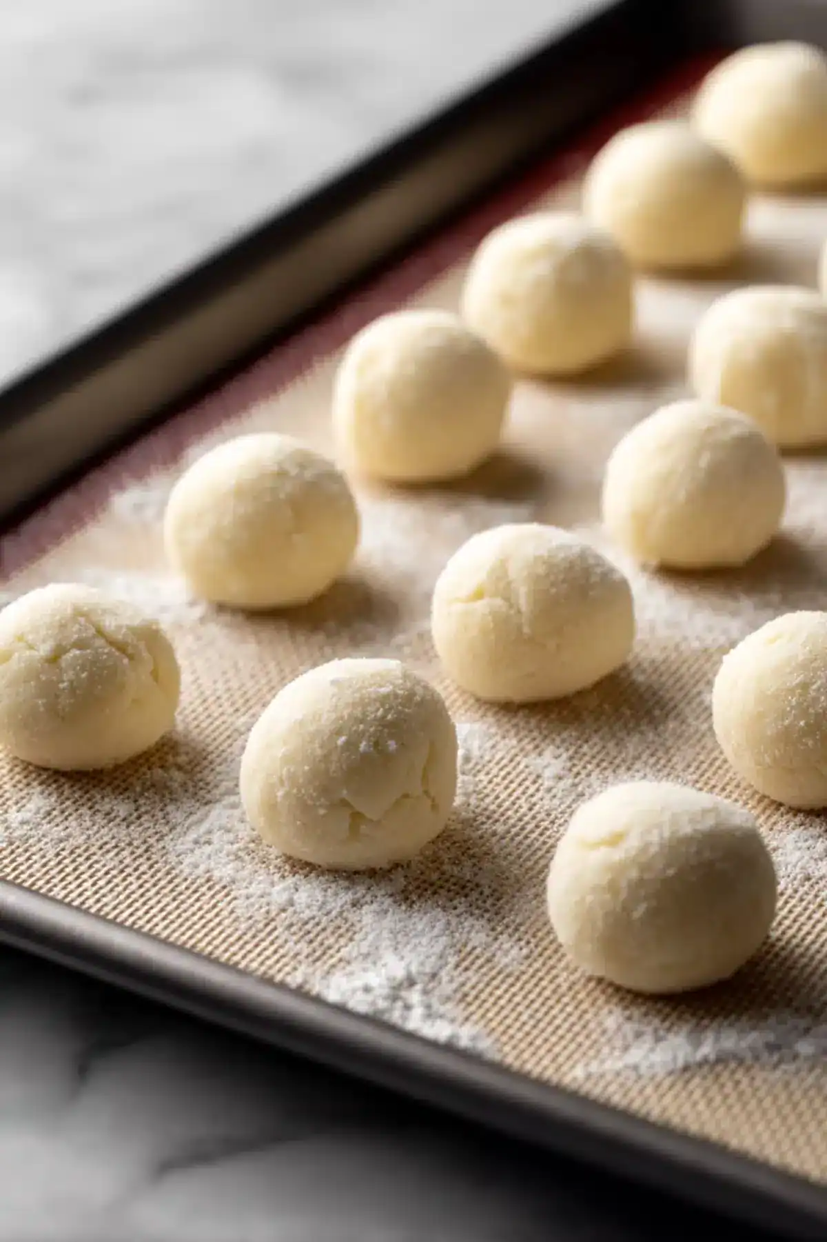 Buttery cookie dough balls on baking sheet for homemade cookies.