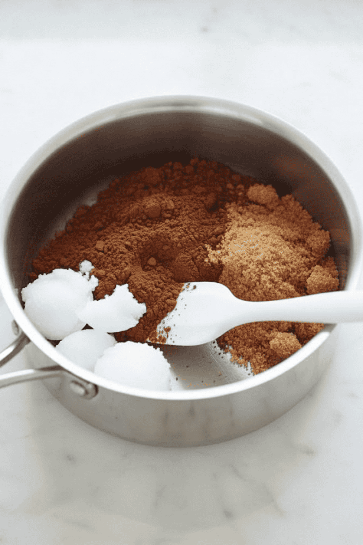 Delicious chocolate cookie ingredients ready for baking, including cocoa powder, marshmallows, in a metal bowl.
