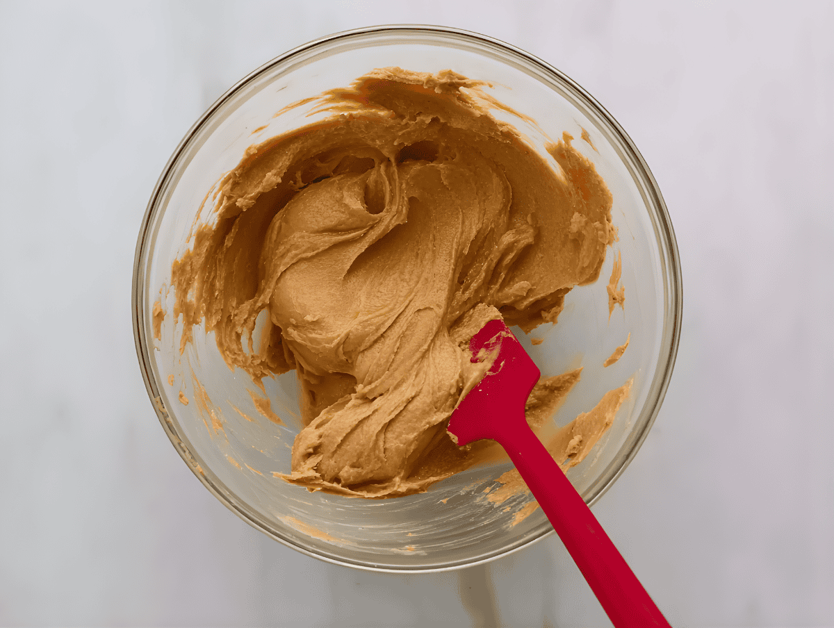 Creamy, abundant cookie dough in a glass bowl with a red spatula, ideal for homemade cookie recipes and baking treats.