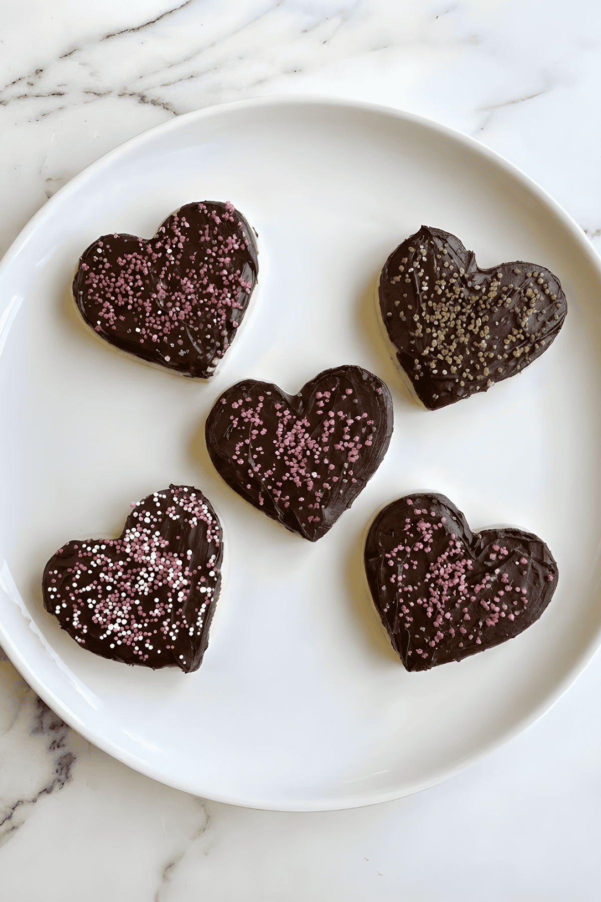 Delicious homemade chocolate heart-shaped cookies decorated with pink and gold sprinkles. Perfect for Valentine’s Day.